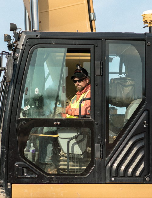 Contour Employee Operating A Bulldozer Wearing Neon Safety Vest & Sunglasses At Job Site