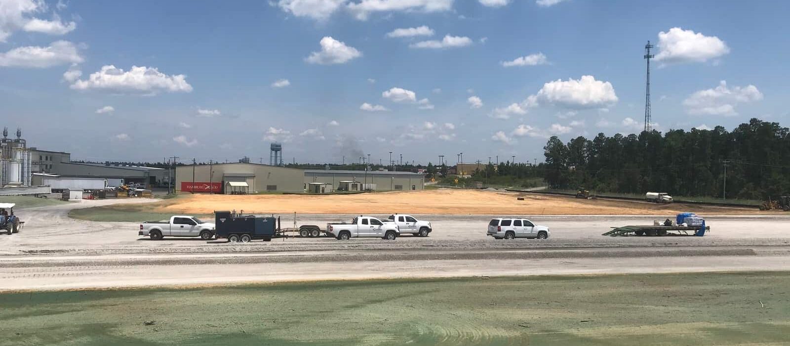 View of an industrial construction site with trailers, work trucks, and a freshly prepared building pad.